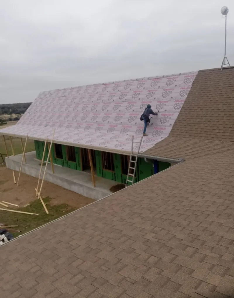 Worker preparing underlayment for a metal roof installation in Lake City